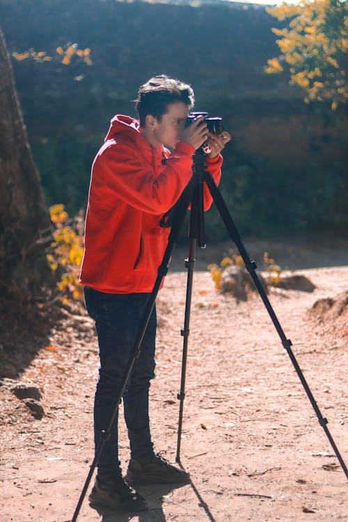 A Man in Red Hoodie Jacket Taking Photos Using DSLR Camera