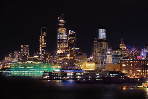 Free Captivating night cityscape of New York City with illuminated skyscrapers reflecting on the water. Stock Photo