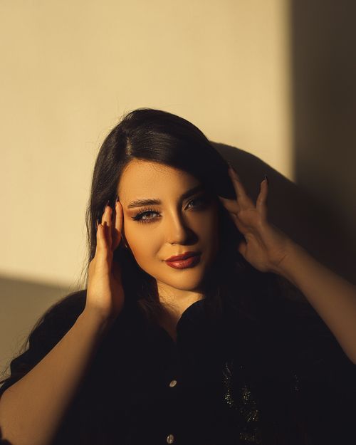 Free A captivating portrait of a woman with red lips and striking shadows in warm lighting. Stock Photo