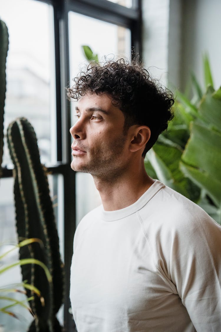 A Curly Haired Man Looking Out The Window