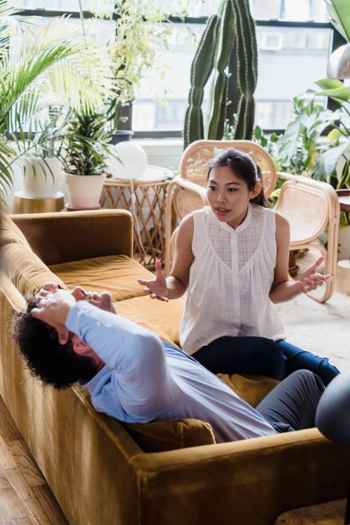 Free A couple talking with expressive emotions in a stylish room filled with plants and natural light. Stock Photo