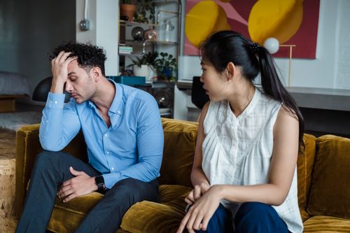 Free Upset couple in a heated discussion sitting together indoors on a sofa. Stock Photo