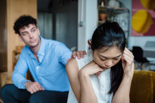 Free Man comforting a woman in a living room, showcasing empathy and support. Stock Photo