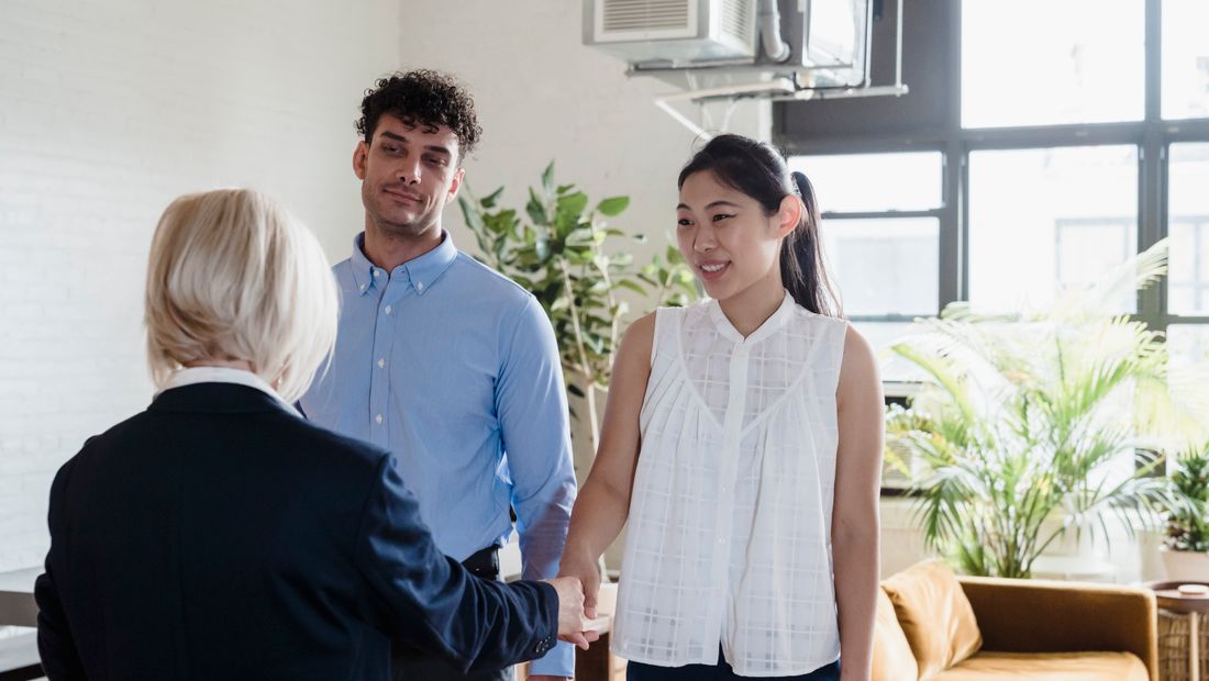 Courtière saluant un couple d’acheteurs au bureau