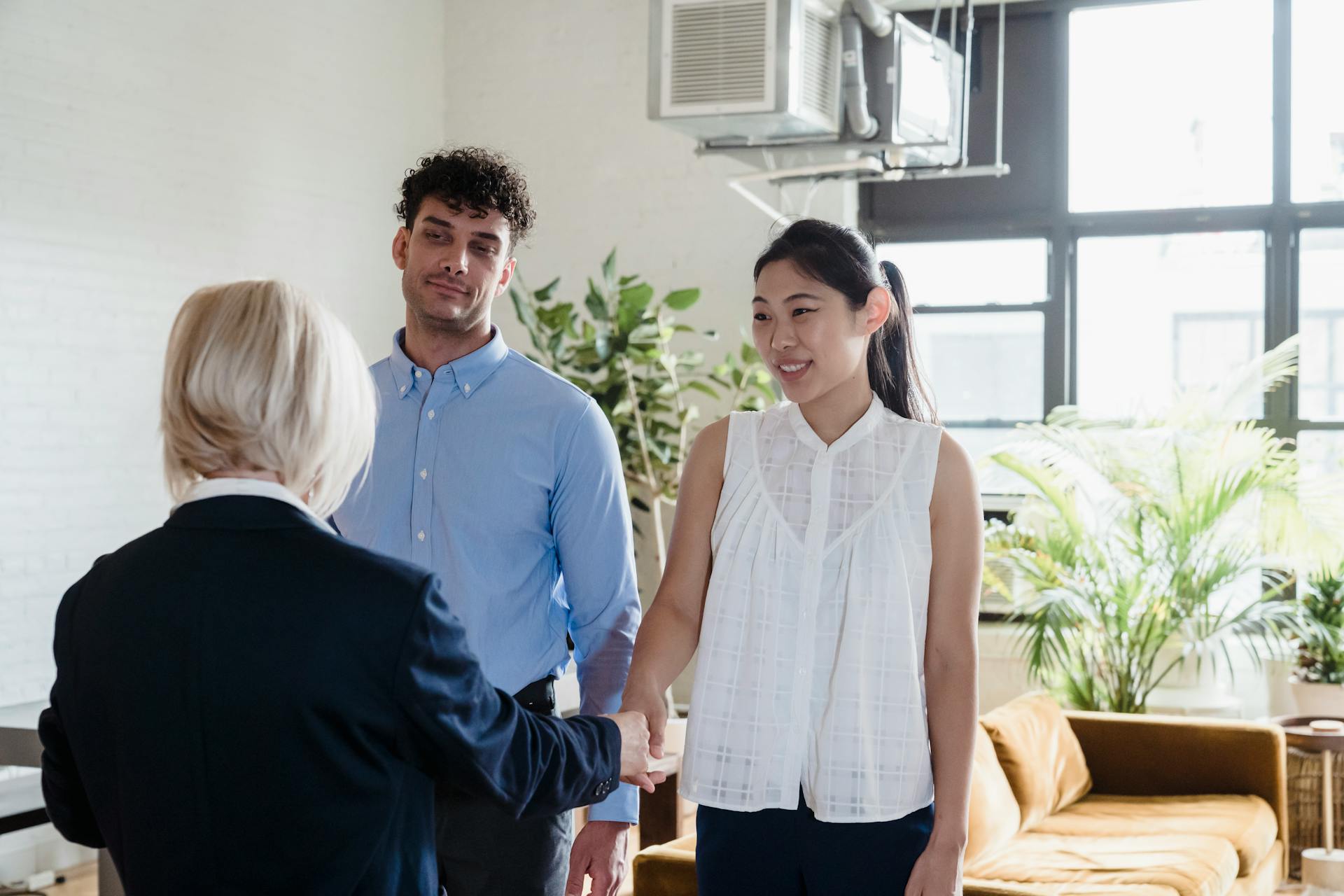 A young couple meeting with a real estate agent in a modern apartment setting.