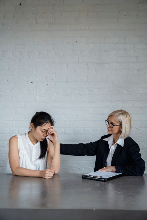 Free Two women having a supportive conversation in an office, one is comforting the other. Stock Photo