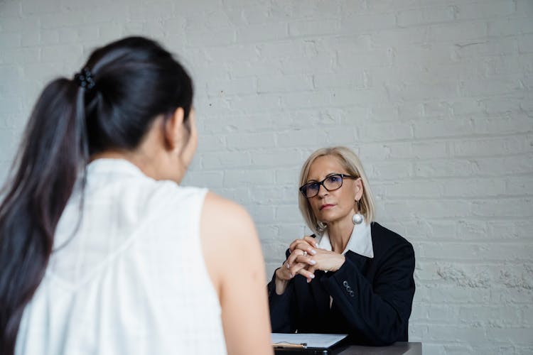 Adult Woman Seriously Listening To The Person Wearing White Sleeveless Shirt