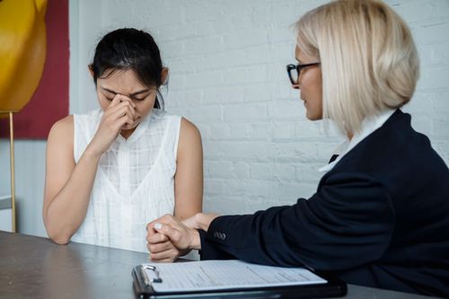 Free Emotional therapy session featuring a supportive female therapist helping a worried young woman. Stock Photo