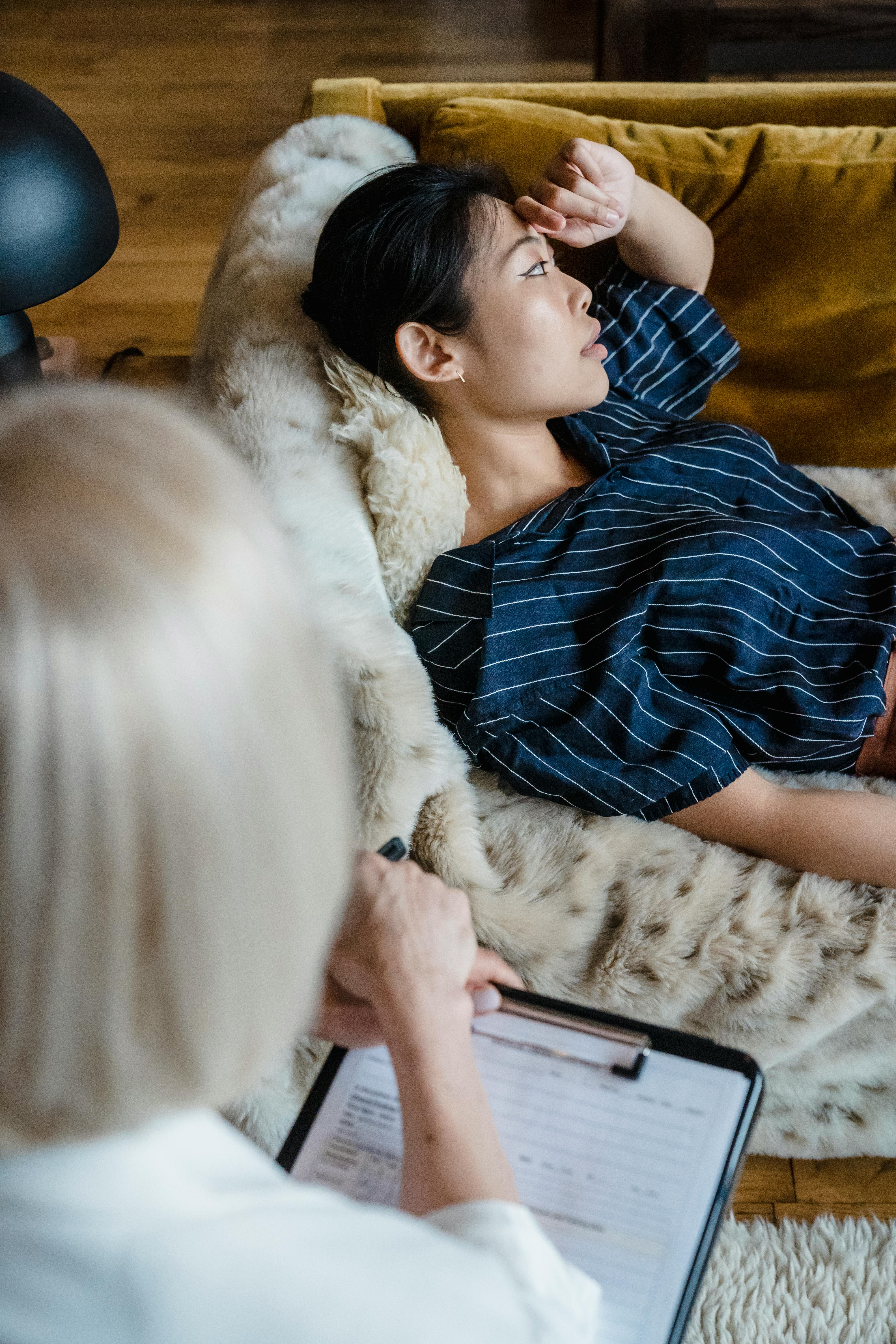Woman lying on sofa discussing concerns during a therapy session with a therapist.