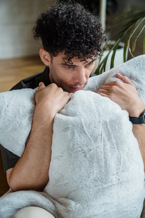 A Sad Man Holding a Pillow 