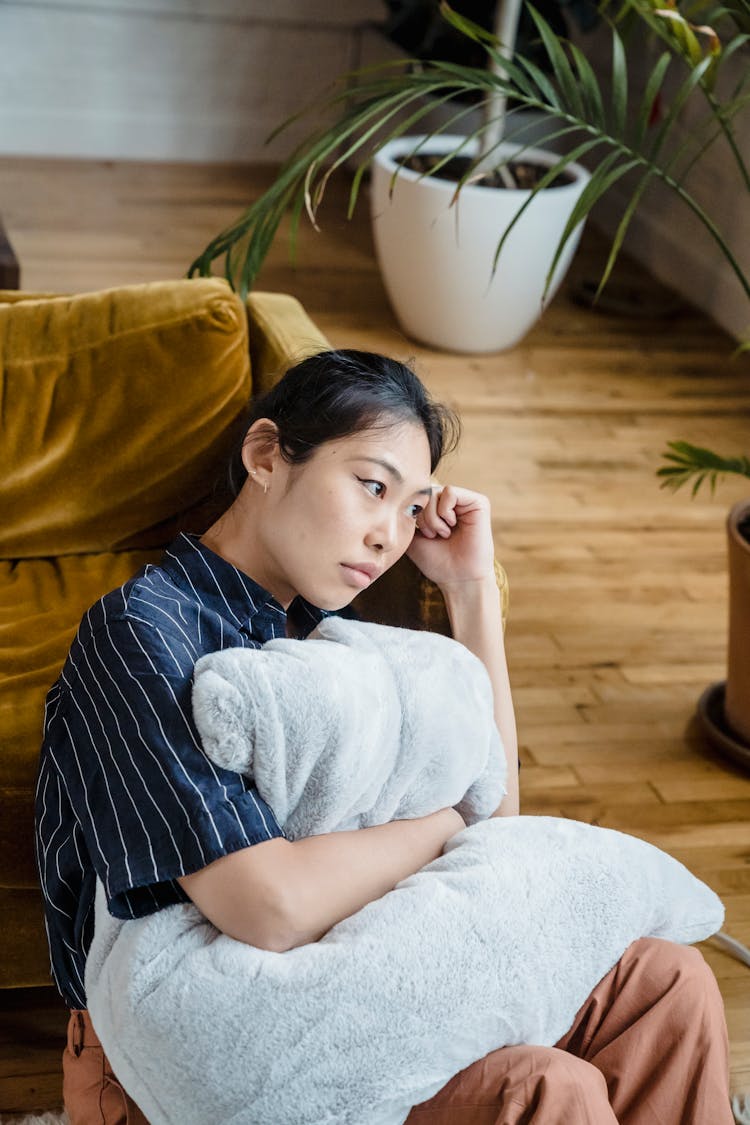 Woman Sitting With Pillow And Thinking