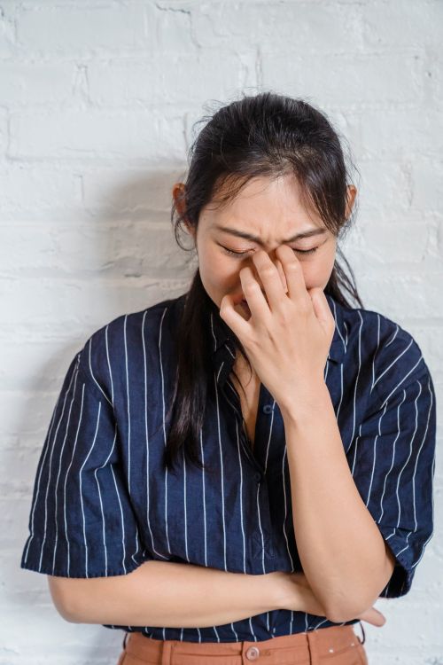 Free A woman expressing emotion while standing against a white brick wall indoors. Stock Photo
