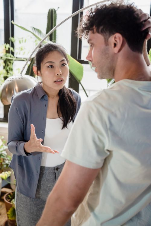 Free A young couple engaging in an intense conversation in a plant-filled indoor space. Stock Photo