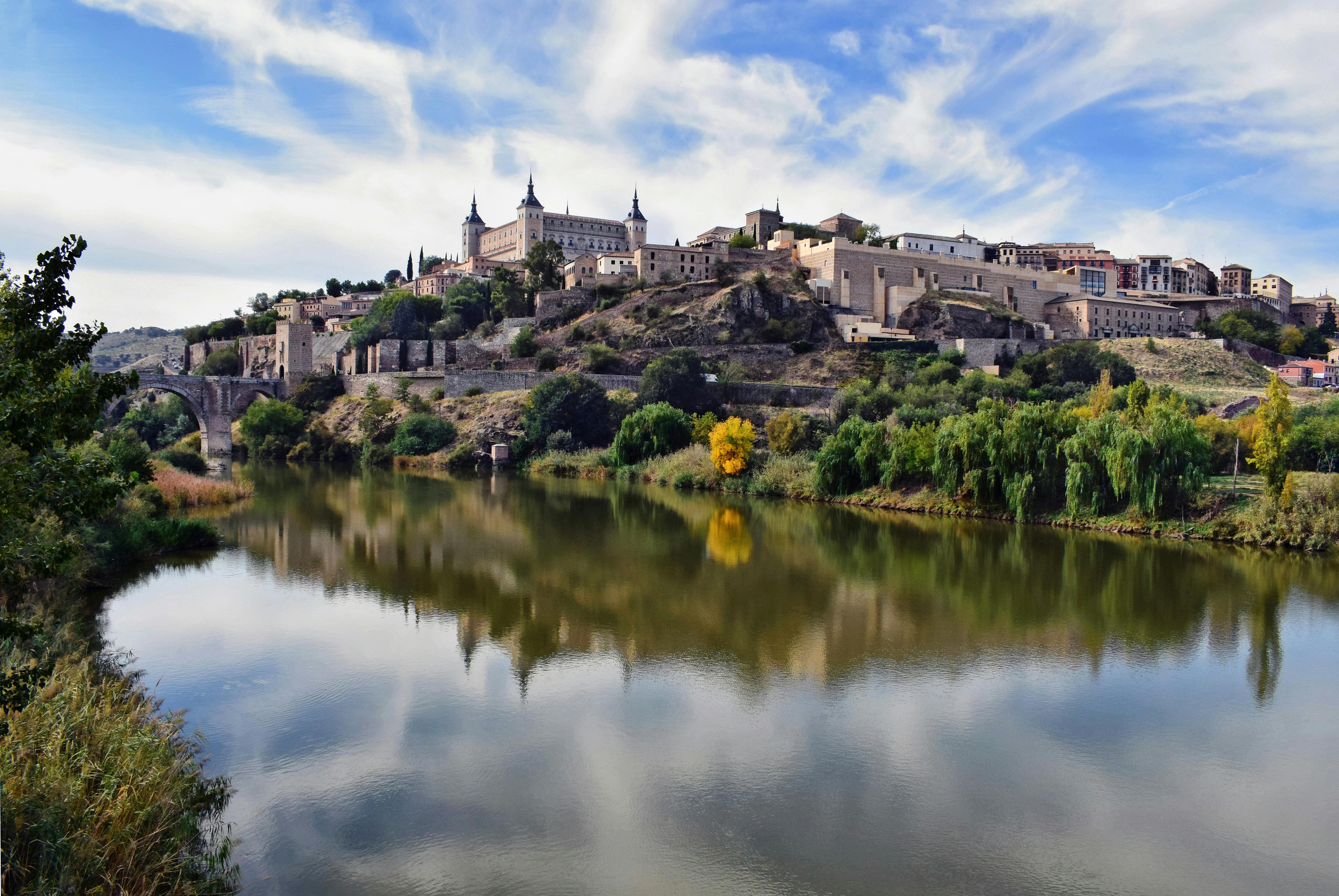 Free Picturesque view of Toledo's historic architecture reflecting in the Tagus River under a vibrant sky. Stock Photo