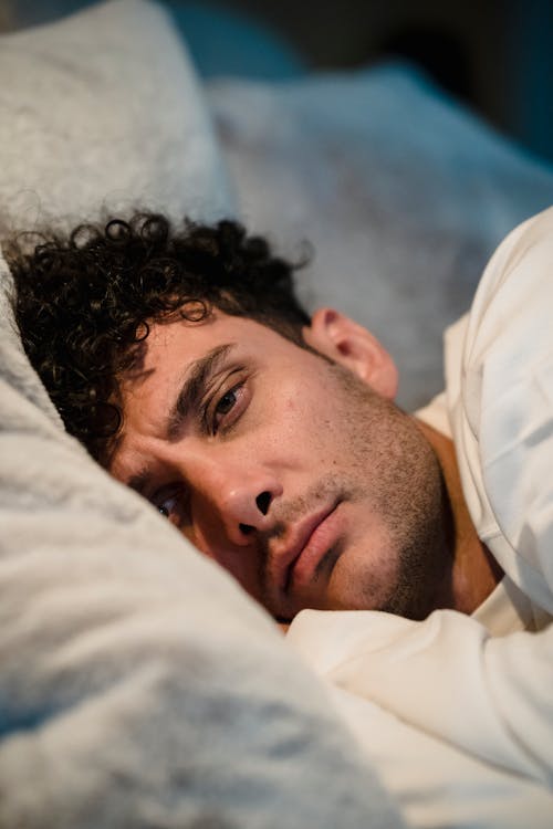 Close-up of Man Lying in Bed and Frowning
