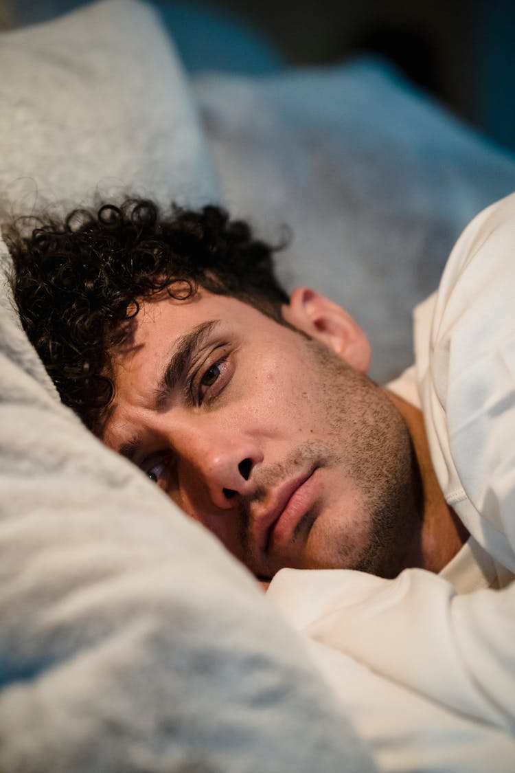 Close-up Of Man Lying In Bed And Frowning