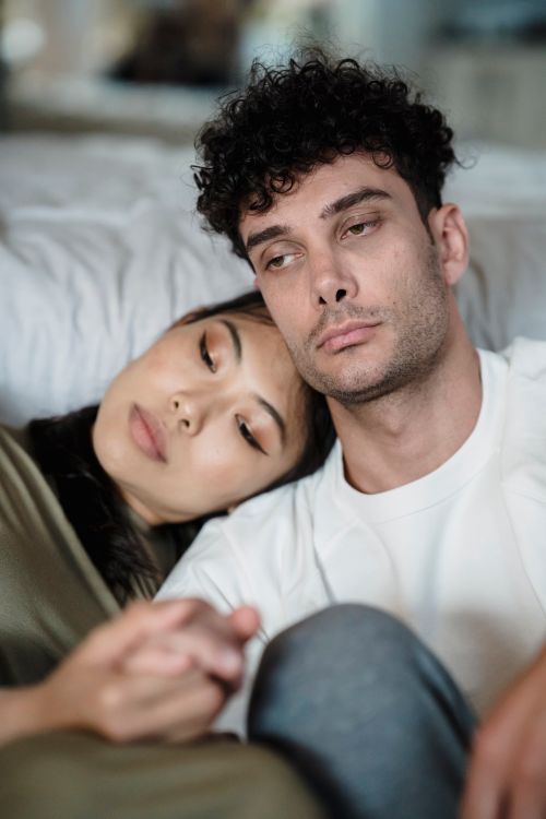 Free Close up of an interracial couple holding hands, capturing a tender and emotional moment indoors. Stock Photo