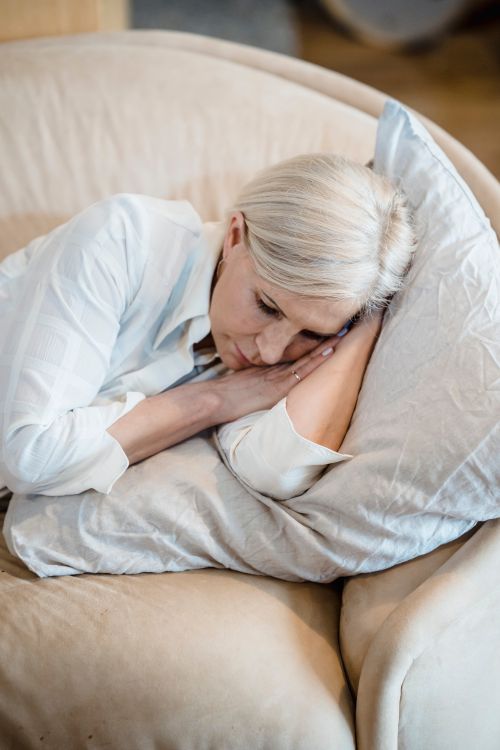 Free A serene adult resting on a cozy couch with a pillow, creating a tranquil atmosphere. Stock Photo