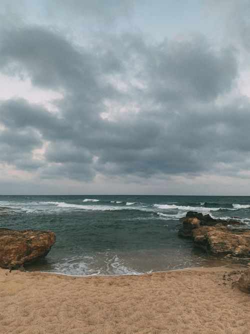 Free A captivating view of the ocean with dark clouds and rugged rock formations. Stock Photo