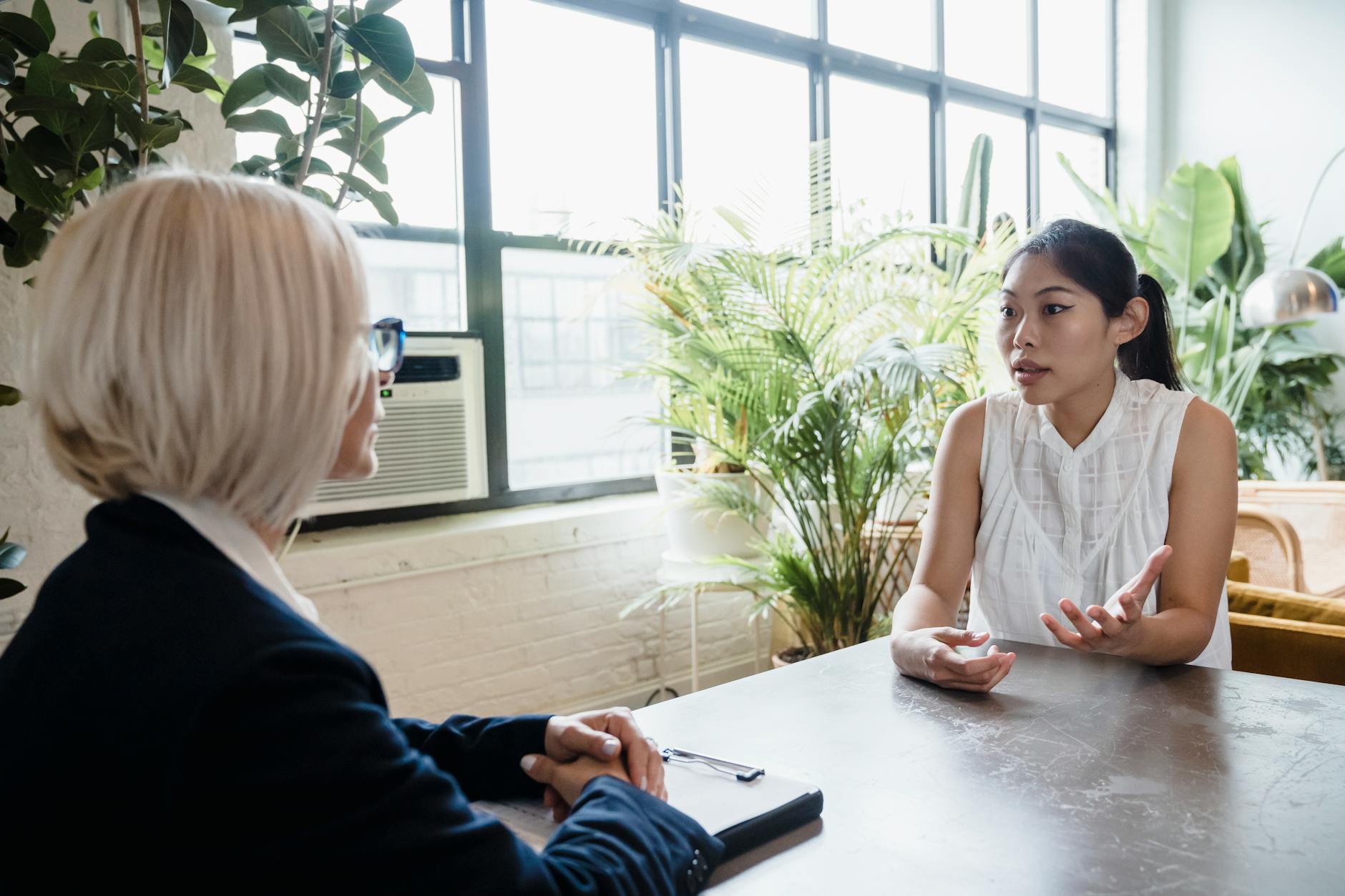 Two women engaged in a professional consultation at a modern indoor office setting.