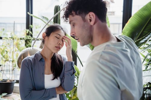 Free A couple experiencing a tense moment surrounded by plants in a modern space. Stock Photo