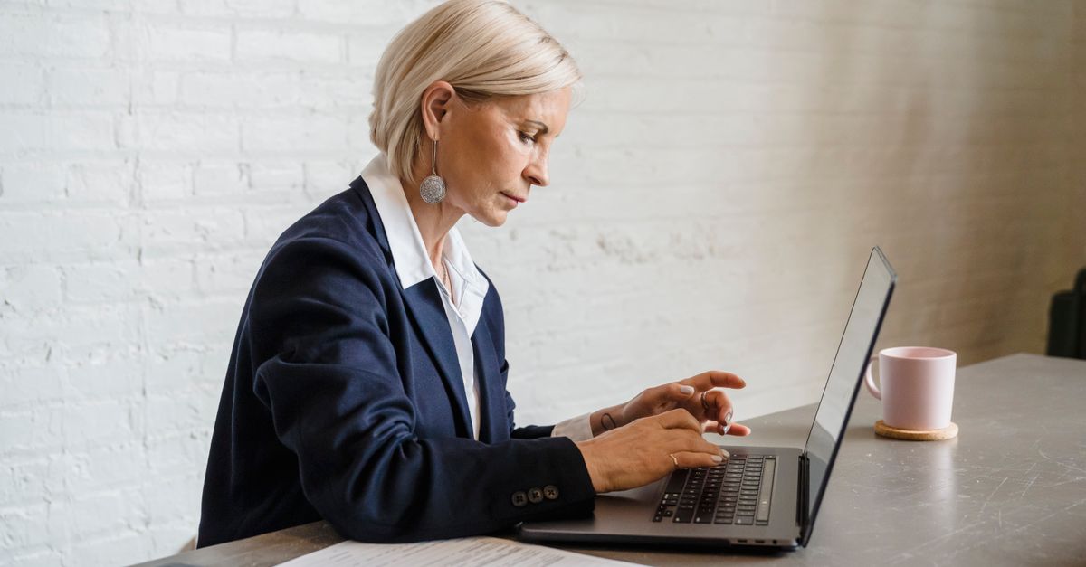 Businesswoman focused on laptop work in office environment, emphasizing productivity.