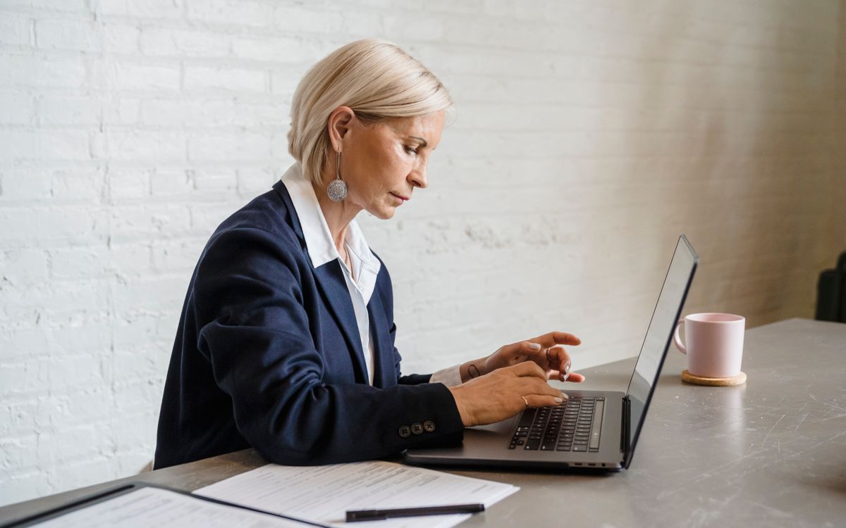 Businesswoman focused on laptop work in office environment, emphasizing productivity.