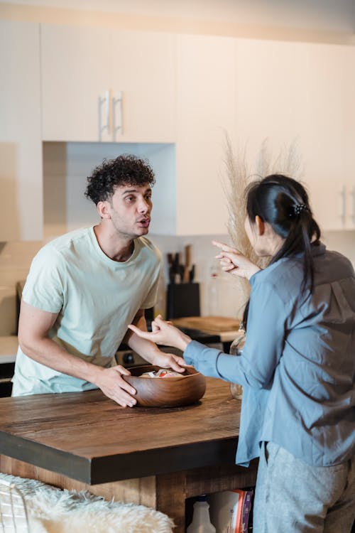 11 Signs A Woman Is Done With You 3 Free A couple engages in a heated discussion in a contemporary kitchen, highlighting relationship dynamics. Stock Photo