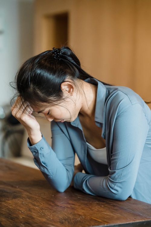 Free Young woman feeling stressed and upset indoors, resting head on hand. Stock Photo
