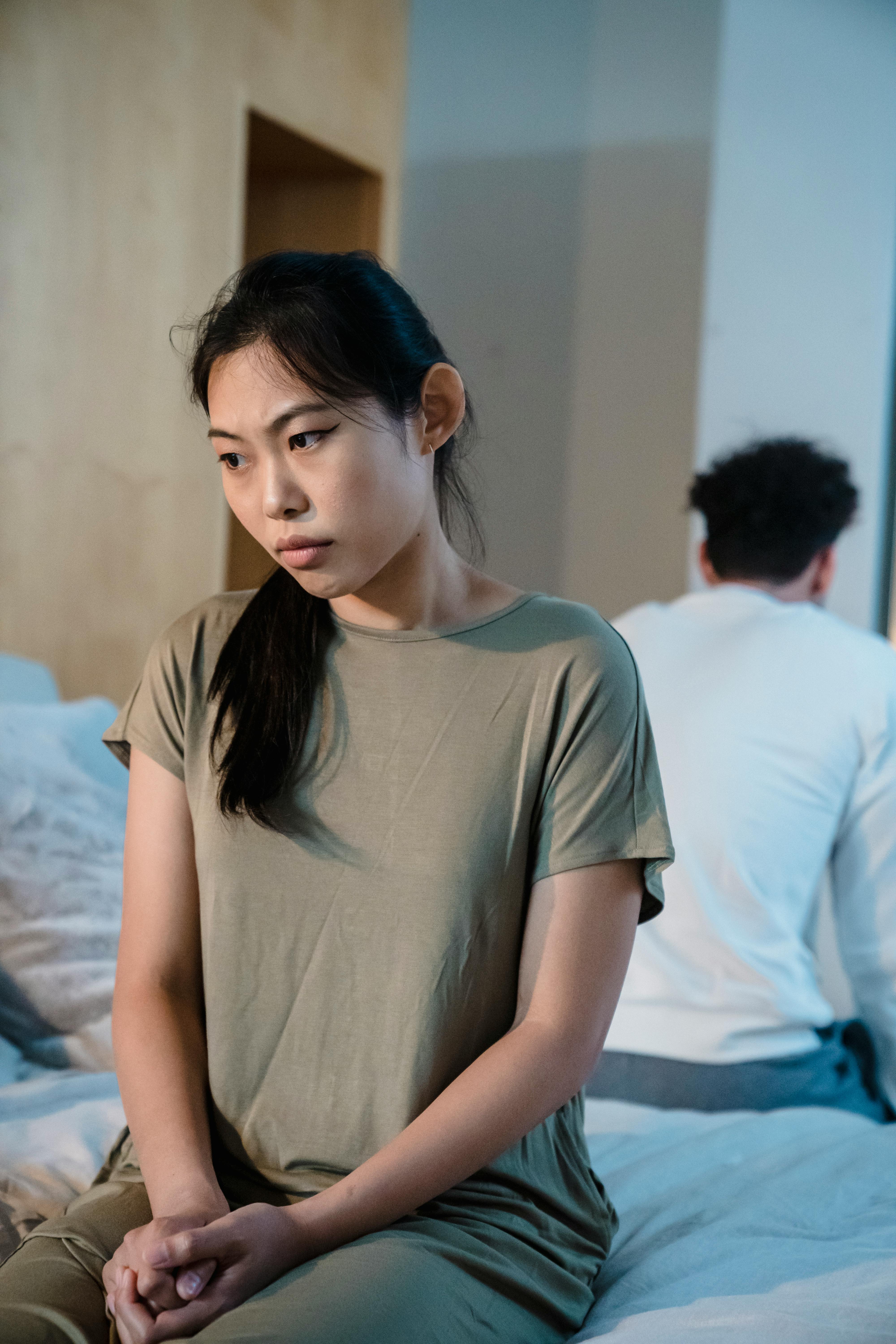 A contemplative couple sitting apart on the bed, expressing emotional distance.