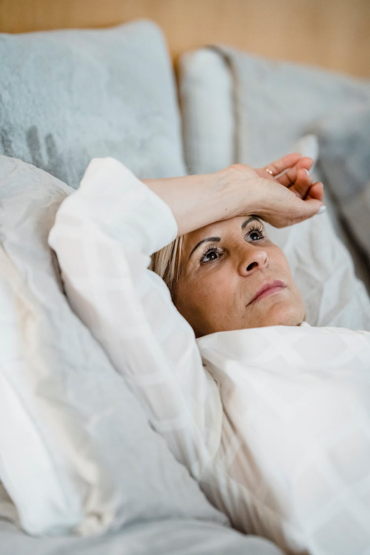 Mature Woman Lying In Bed And Thinking 