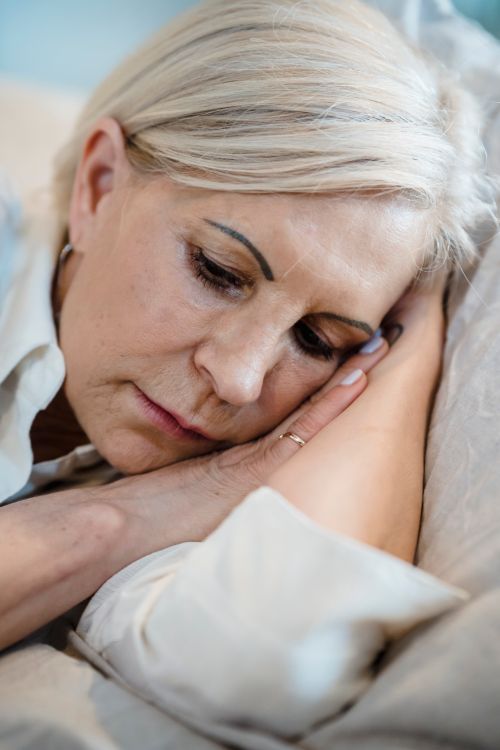 Free A mature woman peacefully lying on a couch, embodying relaxation and tranquility. Stock Photo