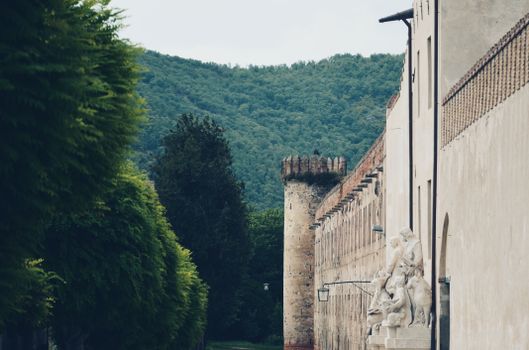 Castle wall with stone sculpture and forested mountain in the background., free online jigsaw puzzle on JigsawPuzzlesFreeOnline.org