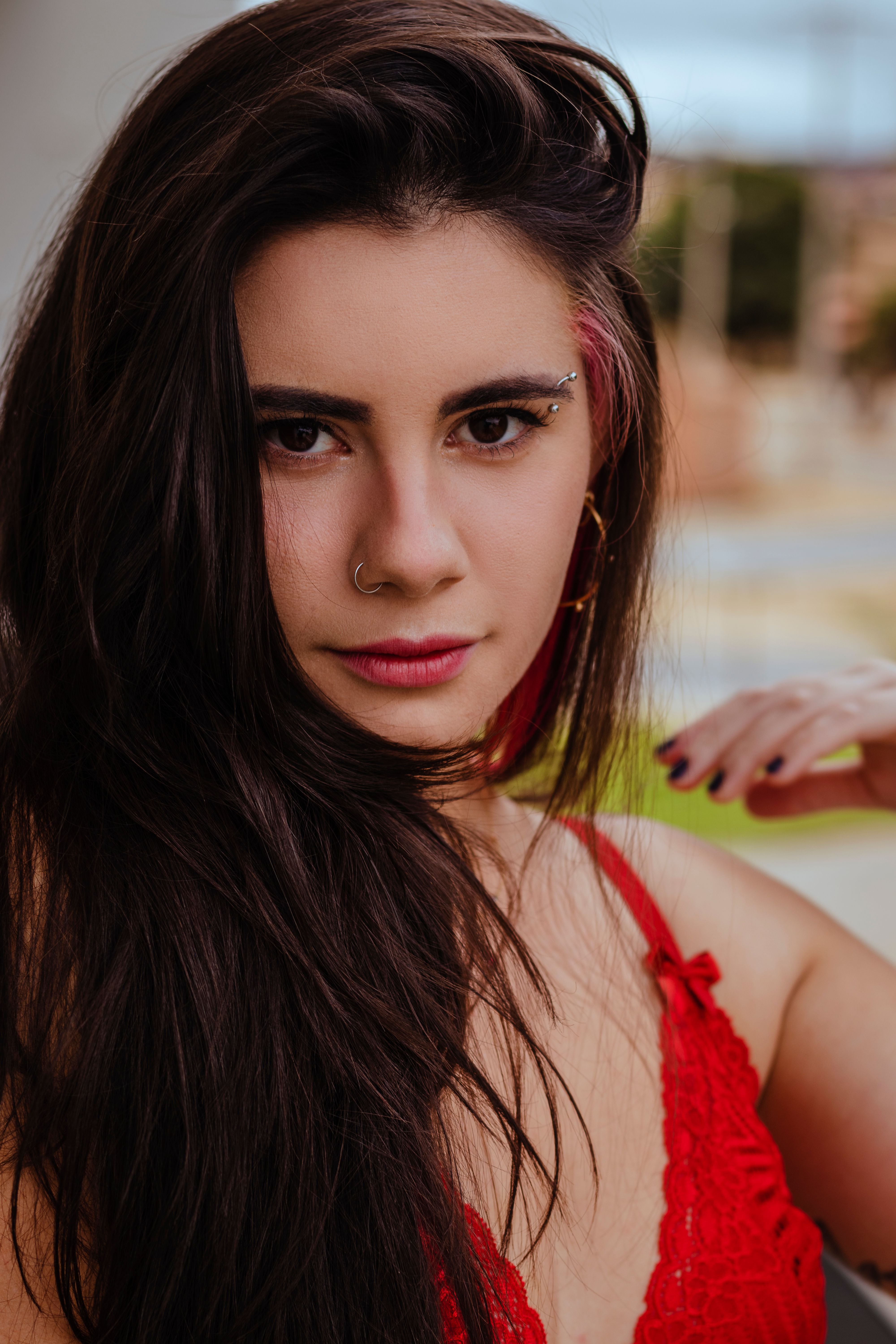 Intimate close-up portrait of a woman with long hair and a nose ring wearing a red top.