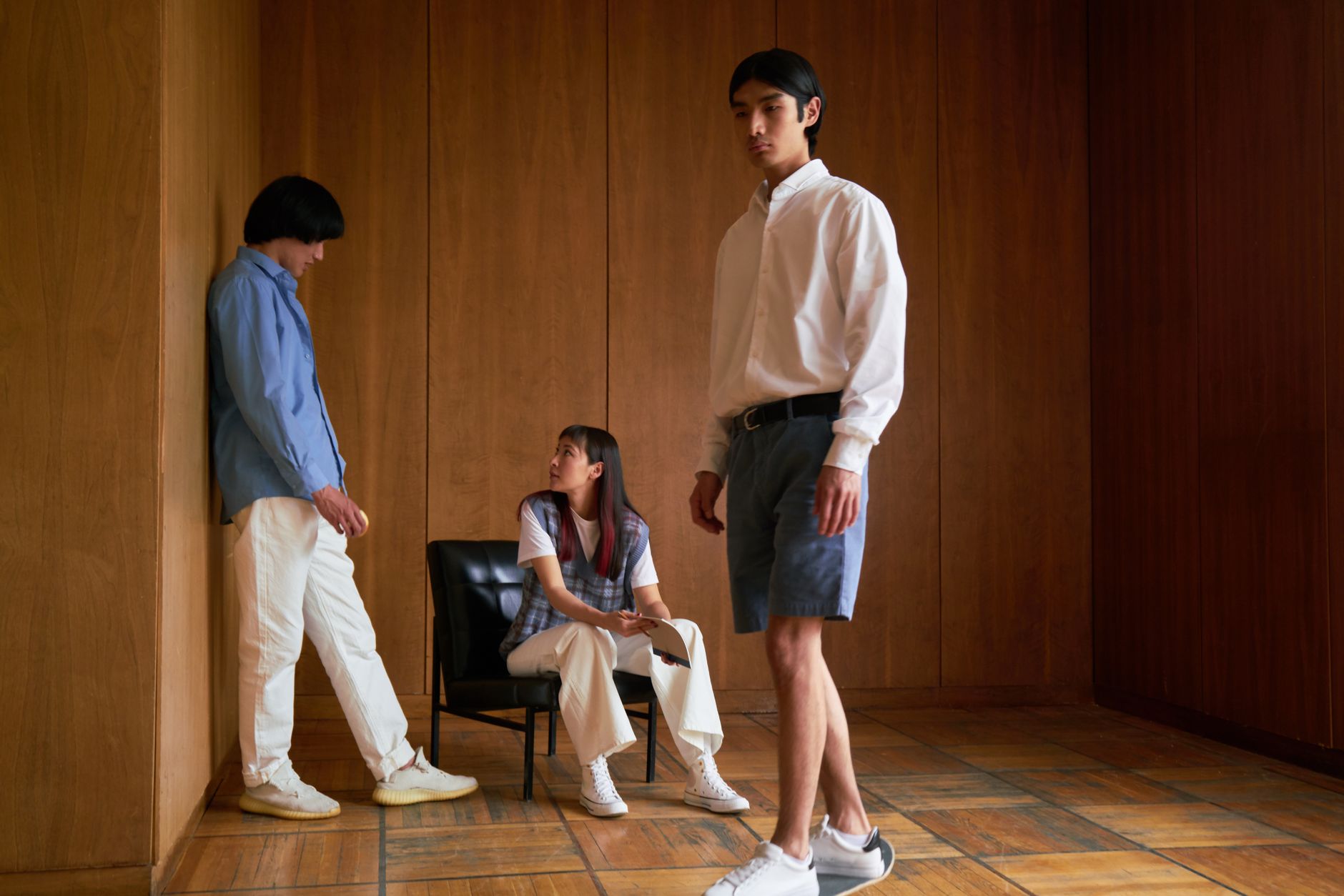Three fashionable young adults pose indoors, showcasing modern style and expression.