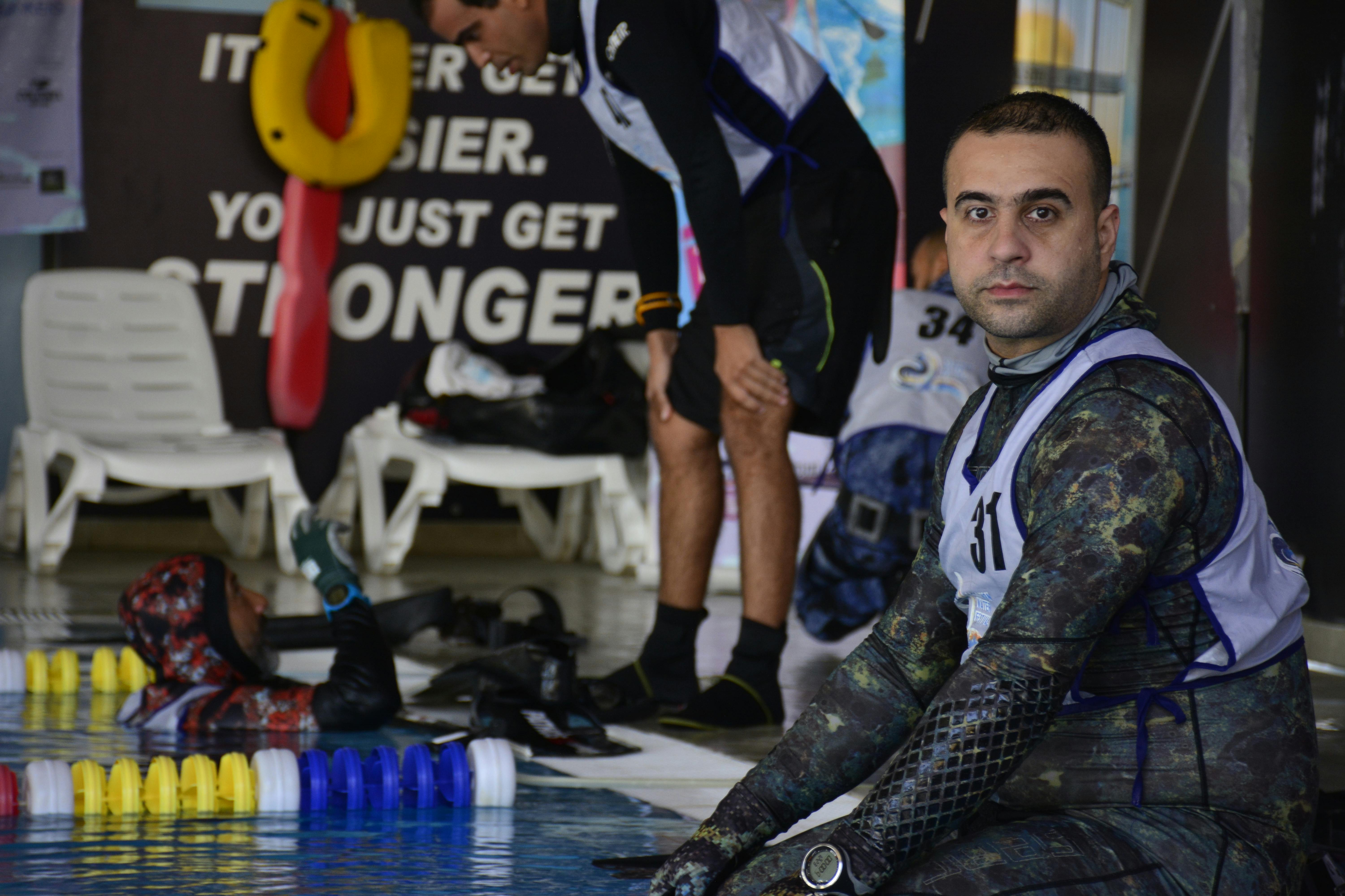 Swimmers in wetsuits getting ready by the poolside, showcasing teamwork and preparation.