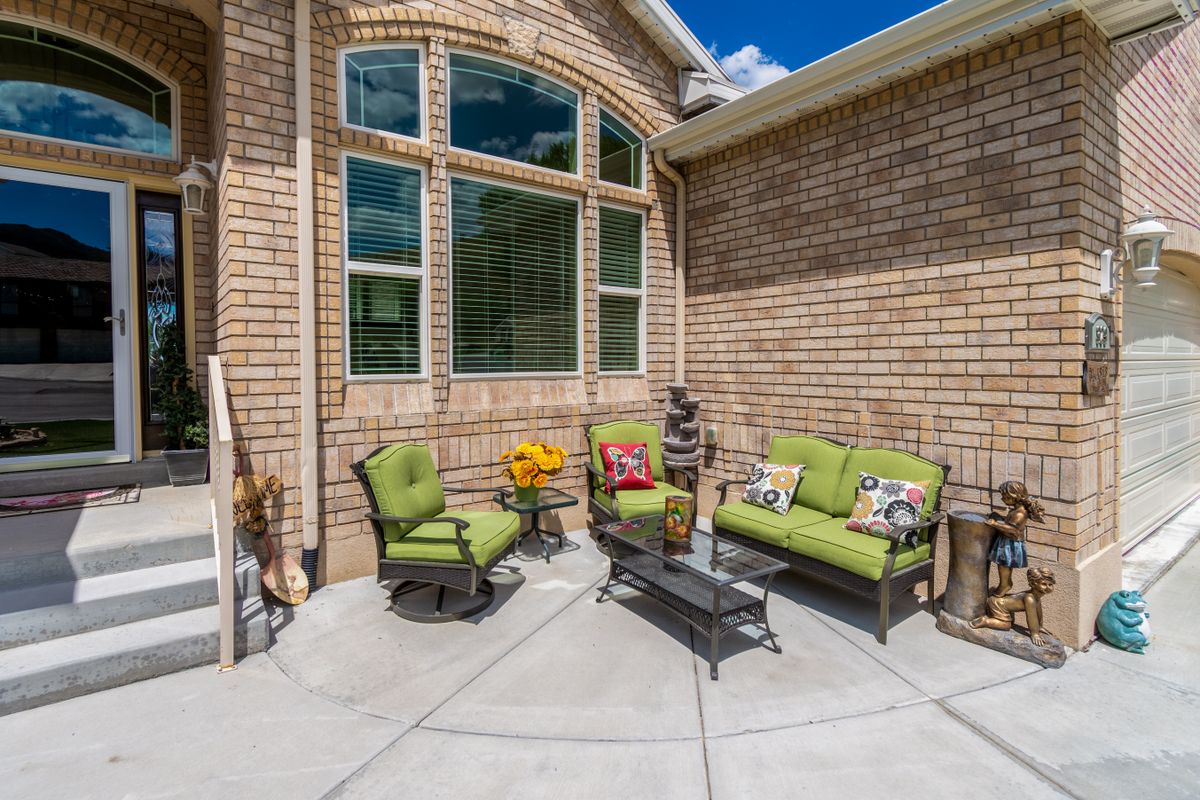 Charming outdoor terrace with green furniture, brick walls, and decorative sculptures, perfect for relaxation. Stock Photo.