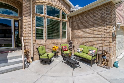 Free Charming outdoor terrace with green furniture, brick walls, and decorative sculptures, perfect for relaxation. Stock Photo