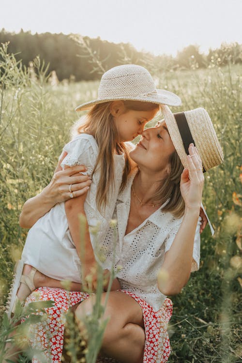Mother and Daughter Sitting on a Grass Field while Facing Each Other
