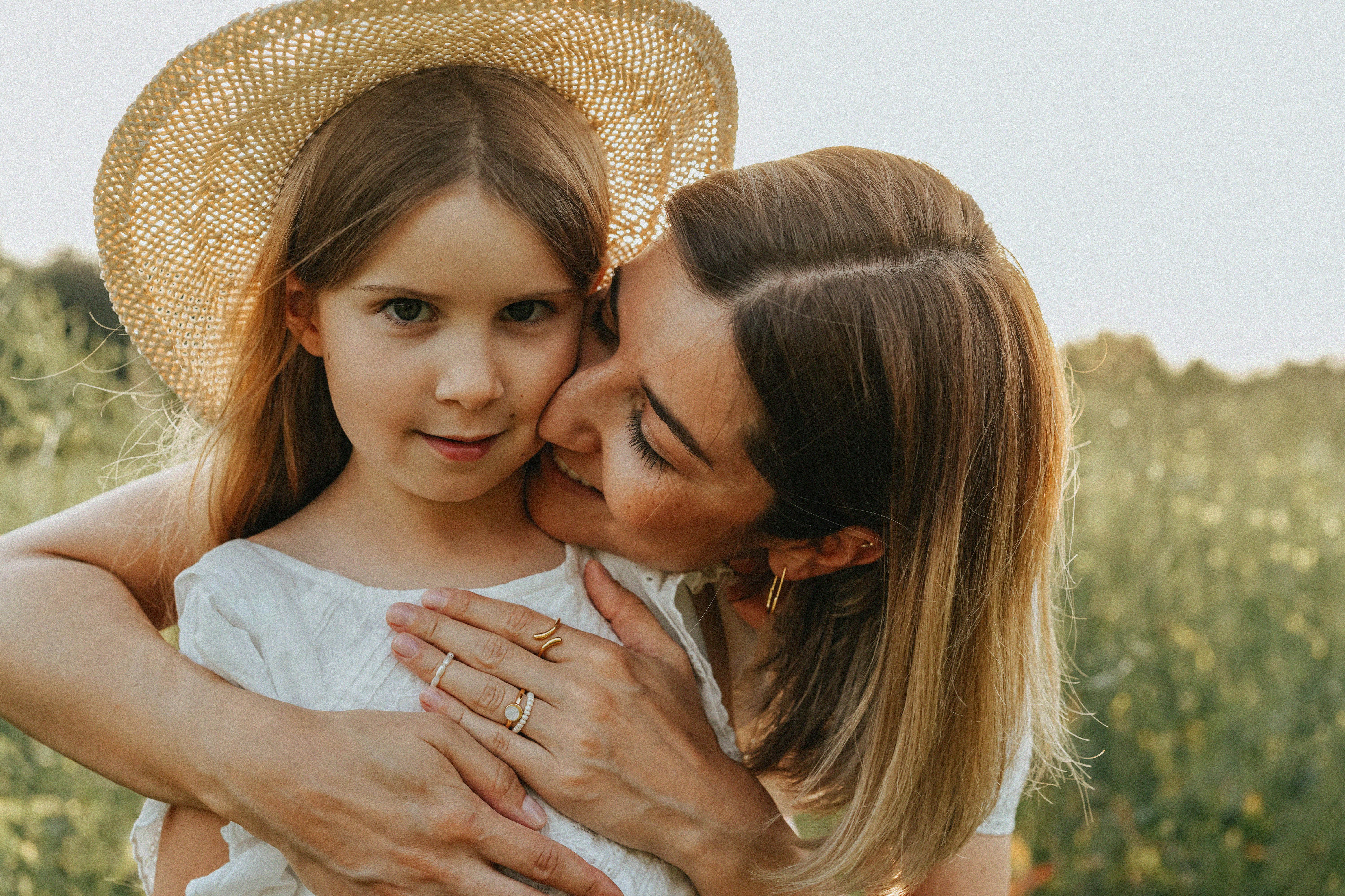 Heartwarming moment of a mother and daughter embracing outdoors in a vibrant summer field.