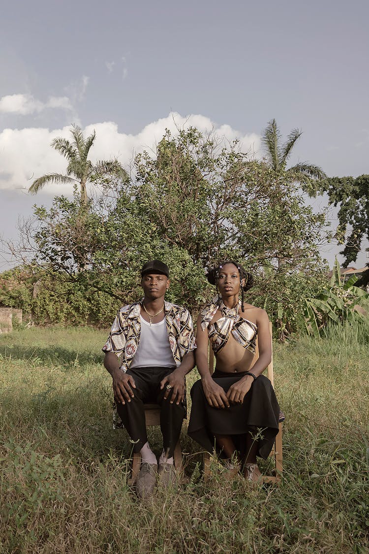 Positive Young Black Couple Sitting On Chairs In Countryside