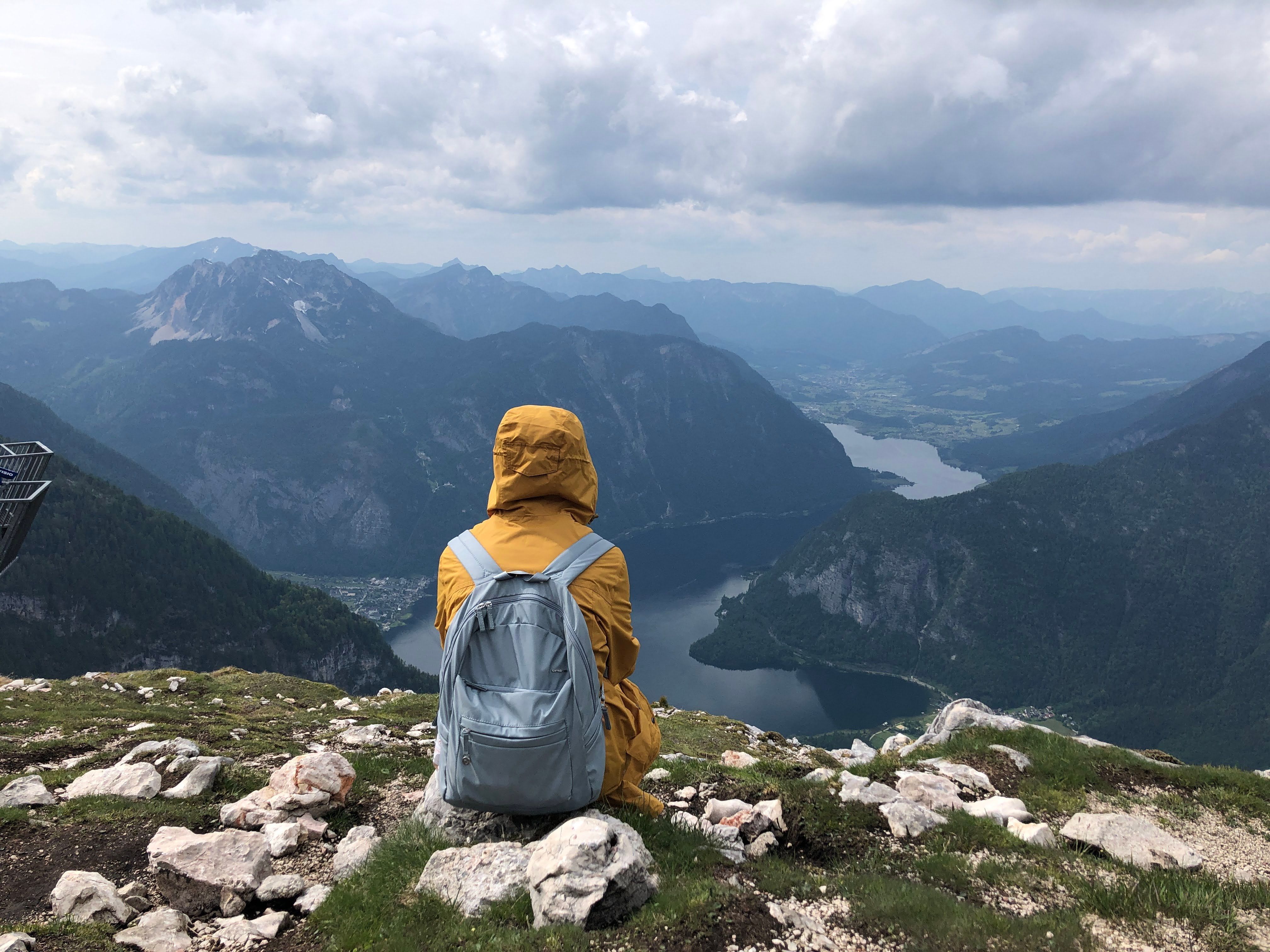 person sitting on a rock overlooking a mountain lake, arms open, no phone in sight
