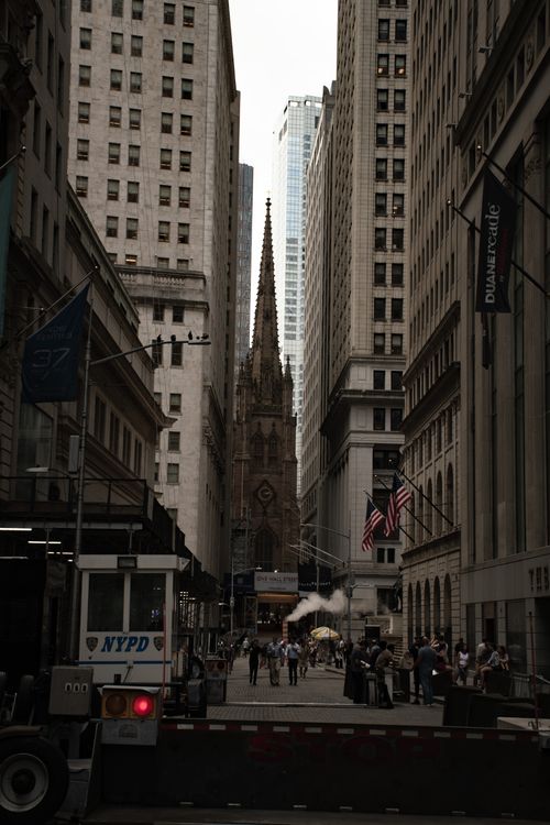 Free Trinity Church in Manhattan framed by towering skyscrapers and bustling street life. Stock Photo