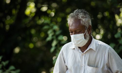 Free Portrait of an elderly man wearing a face mask outdoors, emphasizing safety and protection during a pandemic. Stock Photo