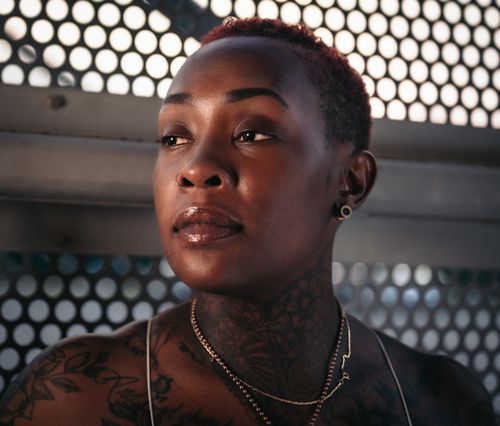 Free Close-up portrait of a woman with tattoos and jewelry, looking away thoughtfully. Stock Photo