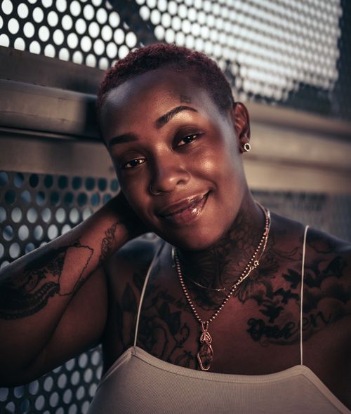 Free Close-up portrait of a smiling African American woman with tattoos, captured outdoors. Stock Photo
