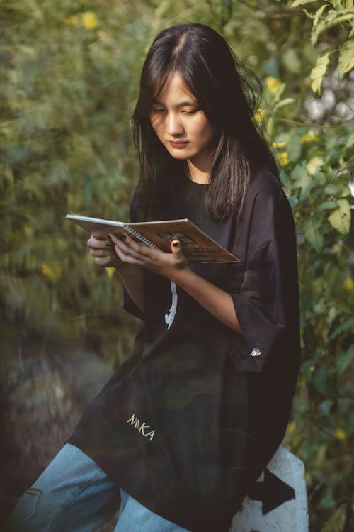 Free Girl in Black Oversized Shirt Reading Notebook Stock Photo