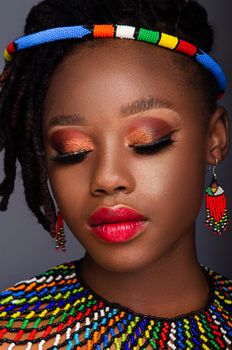 Close-up portrait of an African woman with colorful beads and bold makeup.
