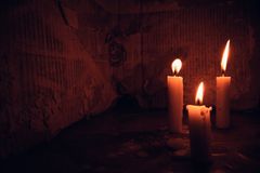 Three candles burn with a warm glow, creating a cozy ambiance in a dimly lit room.