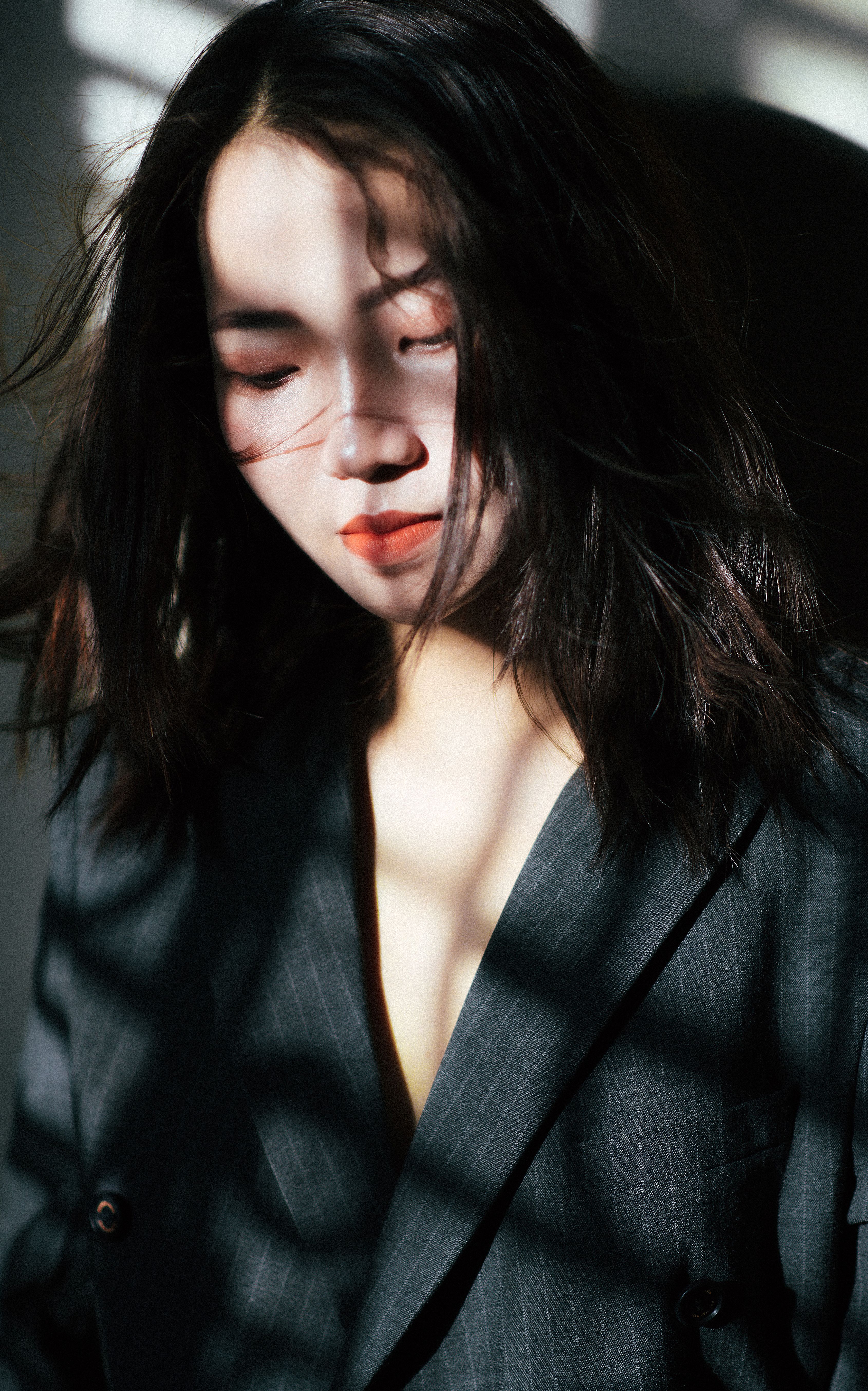 Portrait of an elegant woman in a gray blazer with shadows and dramatic lighting.